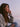 Woman sitting outdoors at sunset wearing a gray cardigan and jeans.