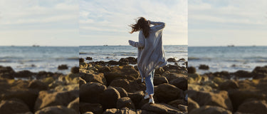 Person standing on rocky beach with ocean view