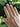Hand wearing two gold rings with a blurred green leafy background